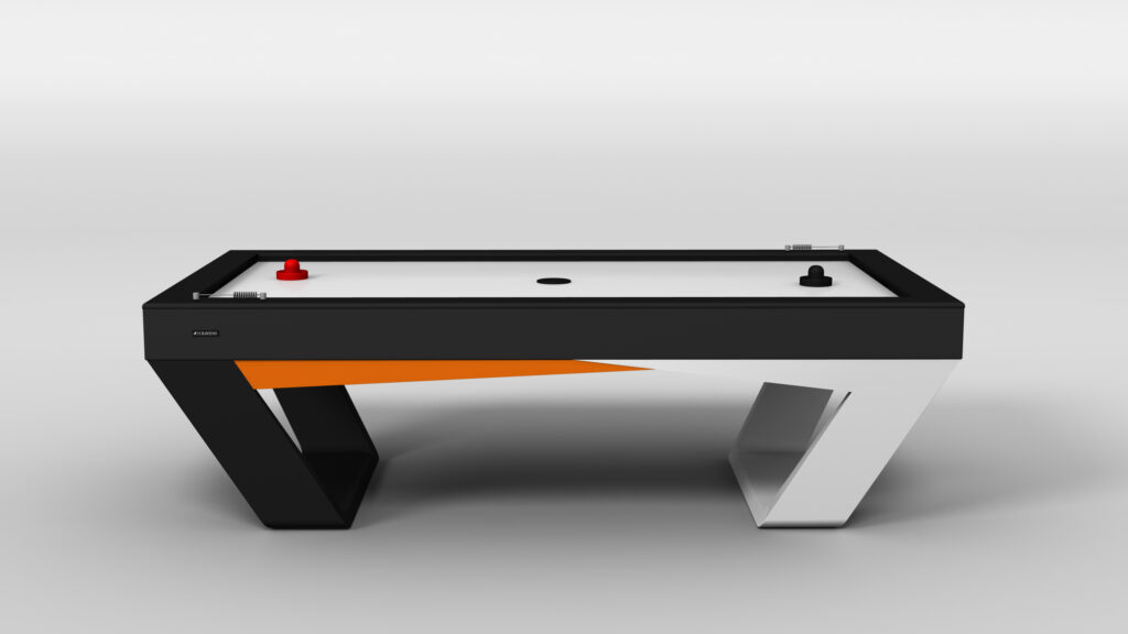 The Avettore Air Hockey Table features a modern black and white design with angled legs, an orange accent, and includes one red paddle and one black paddle displayed on its sleek playing surface.