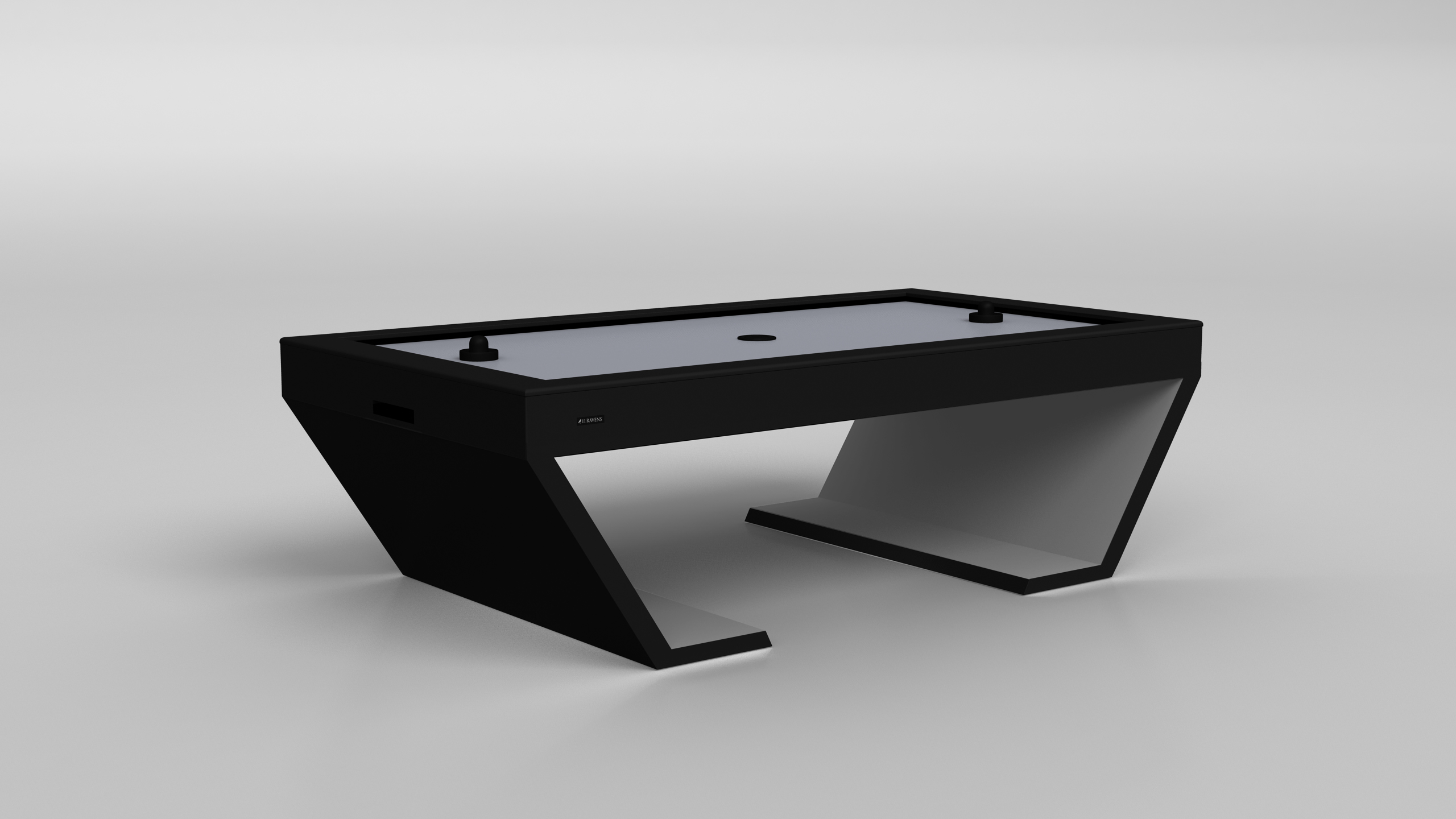 The Cabaret Air Hockey Table, featuring a modern angular minimalist design, sits on a plain light gray background. Two strikers and a puck are visible on its sleek surface.