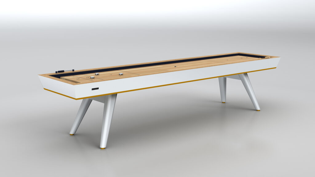 The Hamptons Shuffleboard Table features a light wood playing surface, white frame with yellow trim, and four angled white legs, all set against a plain gray background.