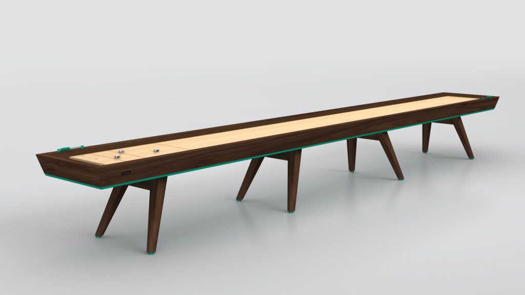 The Hamptons Shuffleboard Table features a sleek wooden playing surface, dark wood frame, and six angled legs. Metal pucks with turquoise accents rest on the surface. Set against a plain light gray background.