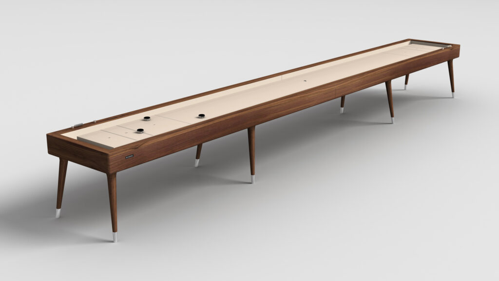 The Hamptons Shuffleboard Table features tapered legs and a smooth, light playing surface. Set against a plain white background, four black pucks are arranged near each end of the table.