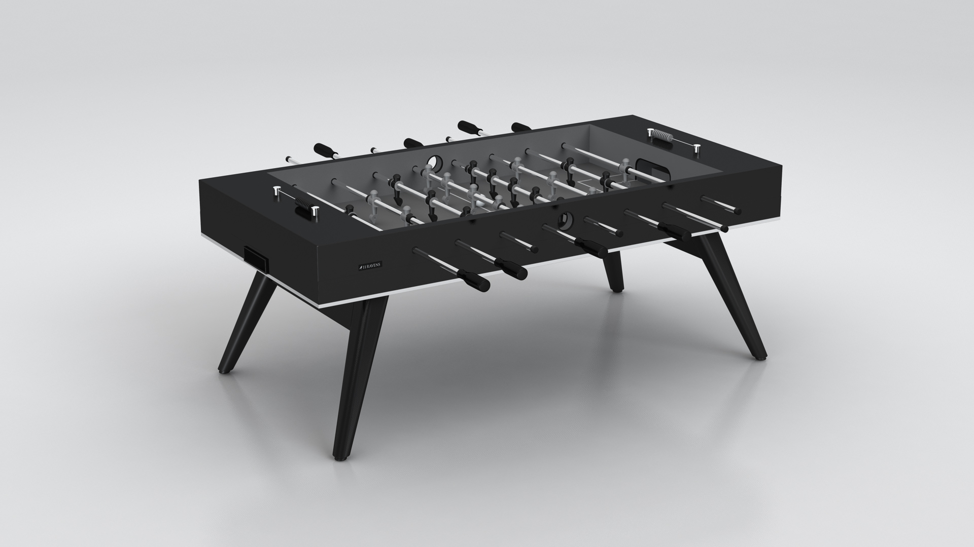 The Hamptons Foosball Table features a modern black finish, minimalist design, black handles, and angled legs, set against a plain light gray background.