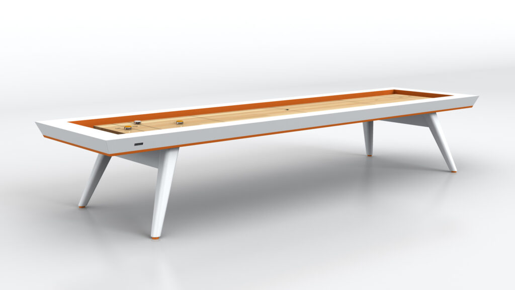 The Hamptons Shuffleboard Table is a modern luxury game piece, boasting a sleek design with a wooden playing surface and angled white legs, highlighted by an orange accent along the edge, elegantly set on a reflective white floor.
