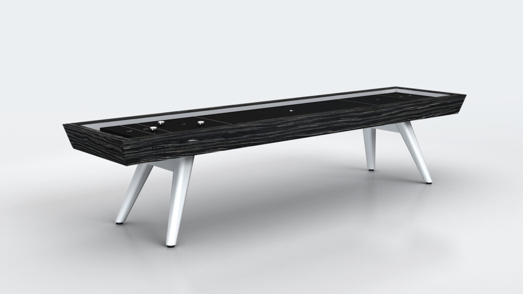 The Hamptons Shuffleboard Table is a luxury game table with a modern look, featuring a sleek black and wood-grain finish, sturdy white angled legs, and set against a minimalist light gray background.