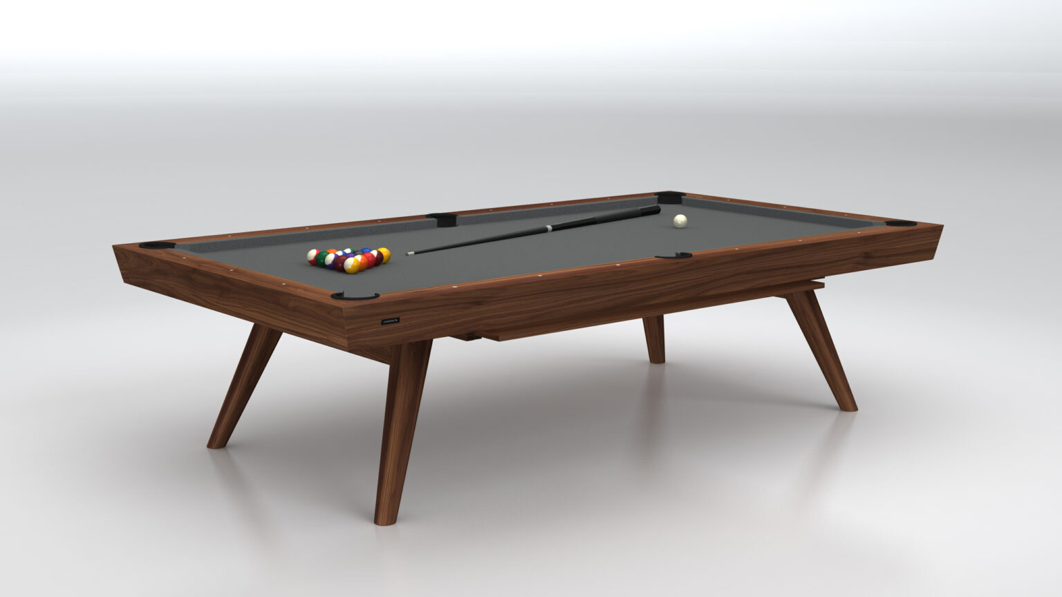 The Hamptons Pool Table is a luxury game table featuring a modern wooden design with a dark playing surface, vibrant billiard balls, a cue stick, and a white cue ball. It stands on sleek angled legs, exuding elegance against a minimalist backdrop.
