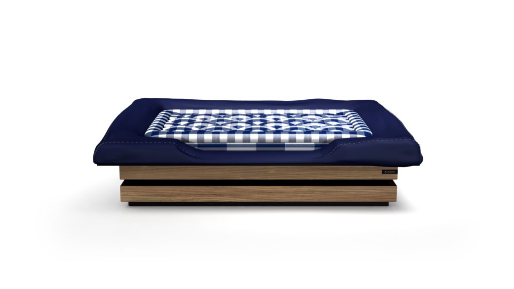 The Arclight Dog Bed is a square, wooden luxury piece featuring a dark blue mattress and a folded checkered blue and white blanket, all against a plain white background.
