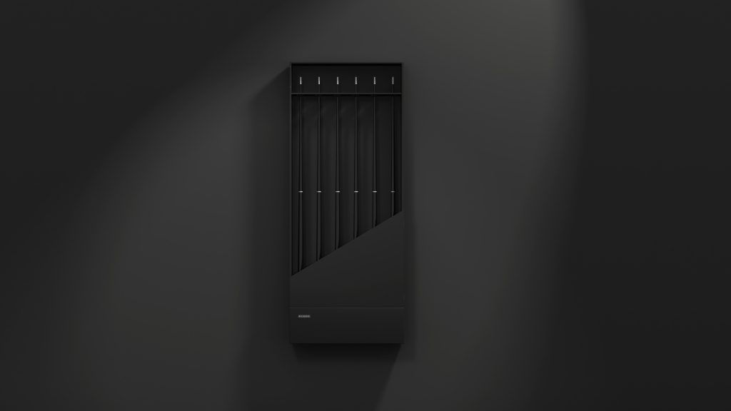 A sleek, modern vertical black radiator with a diagonal panel design adorns a dark wall. Subtle lighting casts shadows, enhancing its minimalist style and luxury appeal—an ideal companion for Arella Cue Rack storage solutions.