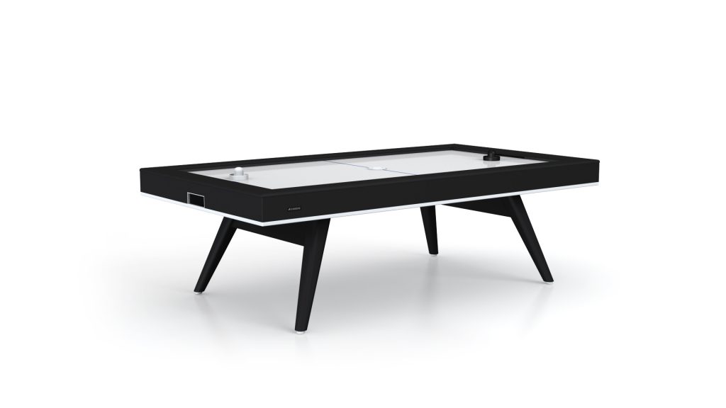 Introducing the Hamptons Air Hockey Table: a sleek, modern design with a black frame and white top. It features stylish triangular black legs, with a black puck and striker on the playing surface, blending sophistication and entertainment perfectly.