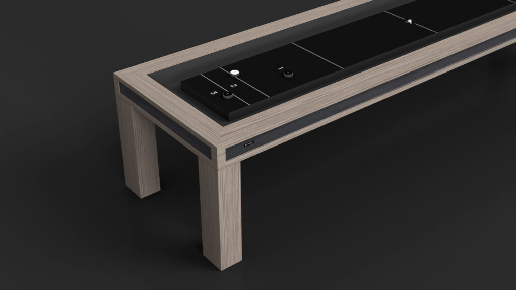 The Malibu Shuffleboard Table is a modern, rectangular wooden table with a built-in black control panel featuring buttons and dials, set against a dark background. A USB port is visible on the side.