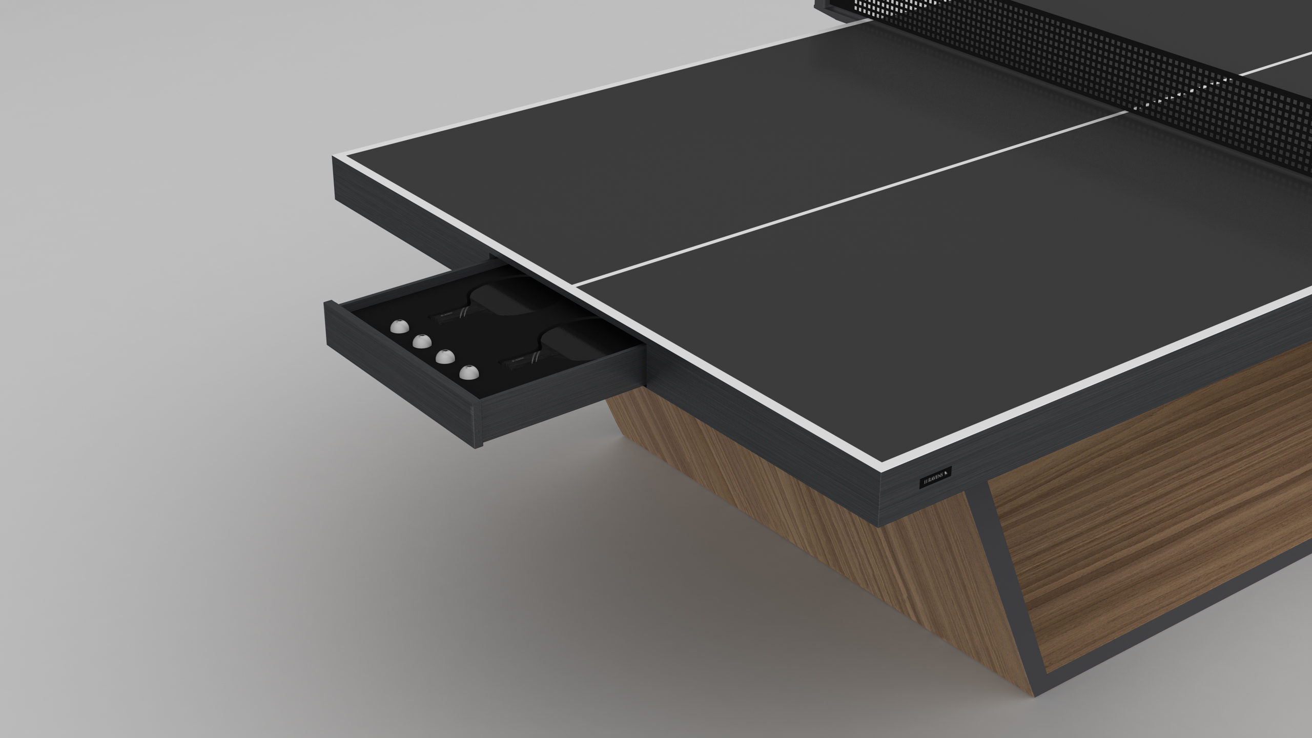 The Mesa Ping Pong Table, featuring a sleek black and wood finish, is shown with an open drawer storing paddles and balls. Attached net included; the table stands elegantly on a light gray surface.