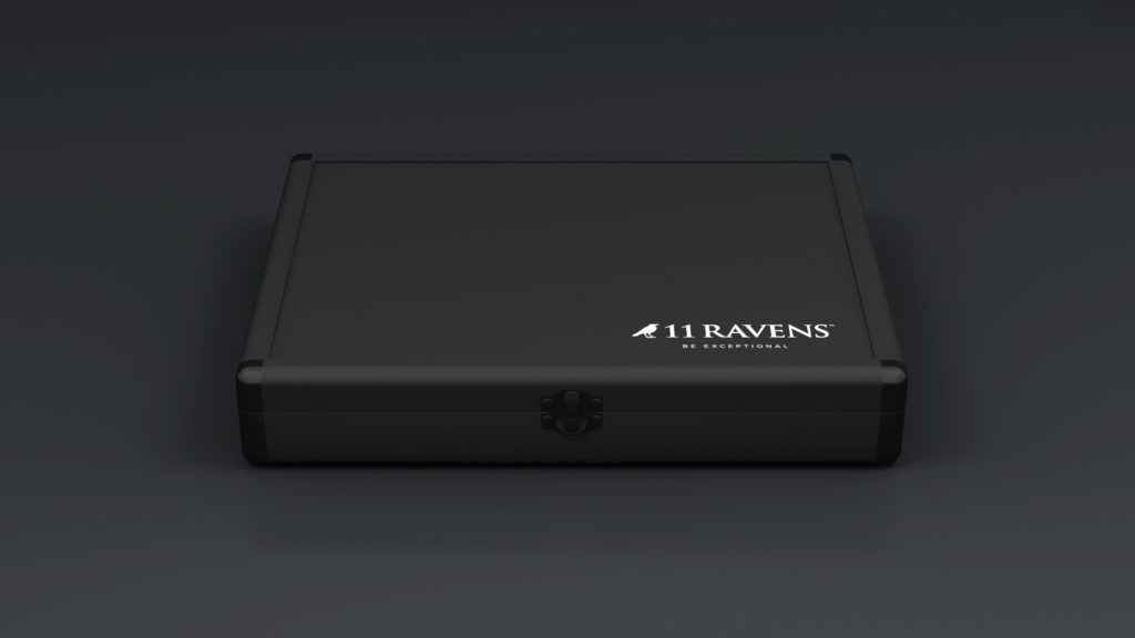 A sleek black rectangular Ping Pong Case features a minimalist design with 11 RAVENS elegantly printed in white on the top right corner, accompanied by a small logo. It has a refined clasp on the front, set against a dark background.