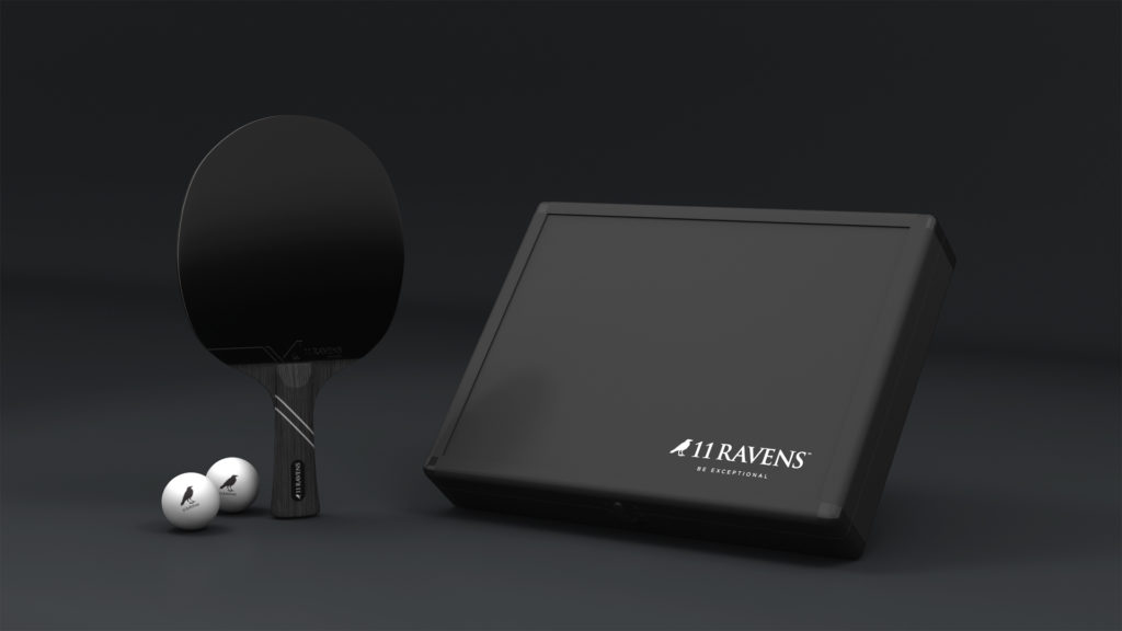 A sleek black ping pong racket and two white balls are elegantly placed beside a luxury Ping Pong Case. The rectangular black case, featuring 11 Ravens - Be Exceptional, stands out against a dark background.