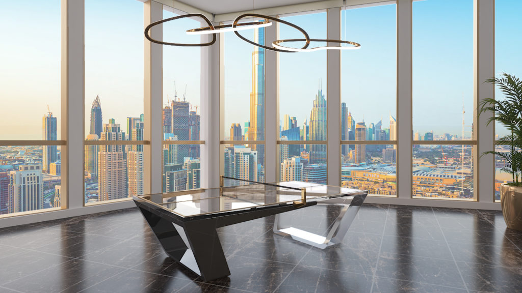 A modern office room features a sleek black desk with cityscape views through large windows, ample natural light, and a contemporary ring light. The corner is enhanced by the luxurious Avettore Lucite Pool Table and a plant for added flair.