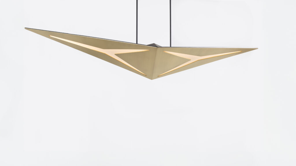 The Áves Pendant Light, featuring two connected triangular panels with illuminated edges, elegantly complements a luxury game table setting. The modern fixture hangs from the ceiling against a plain white background.