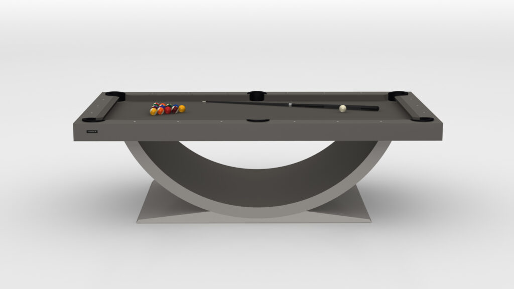The Theseus Pool Table - Outdoor is a sleek, modern luxury game table with a curved base and smooth gray surface, featuring colorful billiard balls arranged in a triangle and an elegantly placed cue stick.