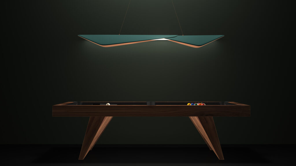 The modern luxury game table with a dark wooden frame is set against a deep green wall. Above, the sleek Folio Pendant Light hangs, casting a soft glow on the table where a cue ball and colored balls are arranged.