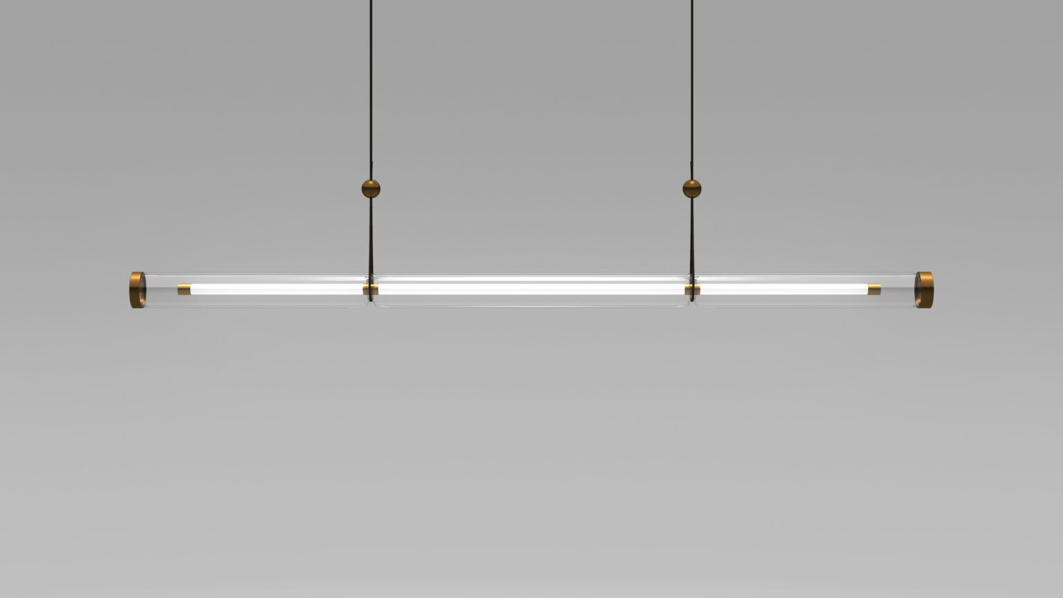 The Cenere Pendant Light boasts a modern, minimalist design with clear tubular glass, suspended by thin black cables. It exudes elegance similar to luxury game tables, featuring small brass accents at the ends and top against a plain gray background.