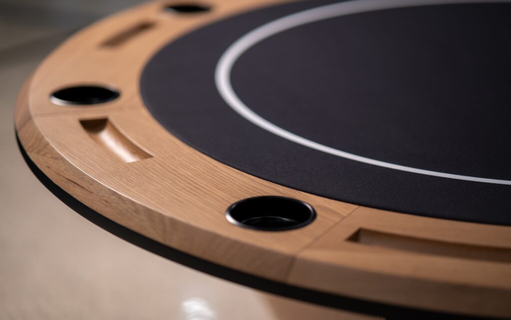 The 5 Theseus Round Poker Table - Off The Floor features a black felt surface with a wooden edge, built-in cup holders, and slots, offering enhanced functionality and design as part of the luxury game tables collection.
