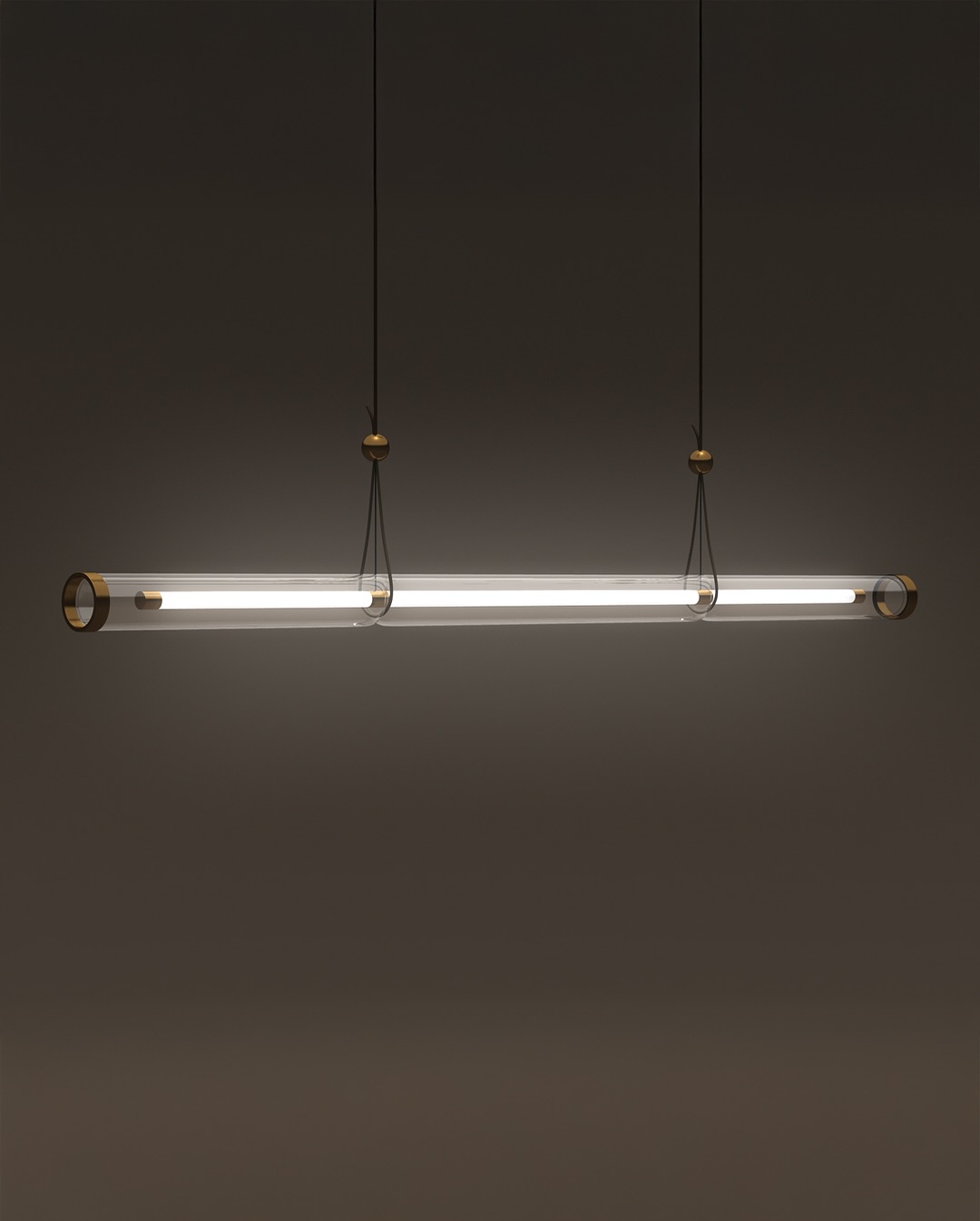 A modern, cylindrical pendant light fixture with metallic end caps, suspended by two cables against a plain, dark background. The light emits a soft, white glow.