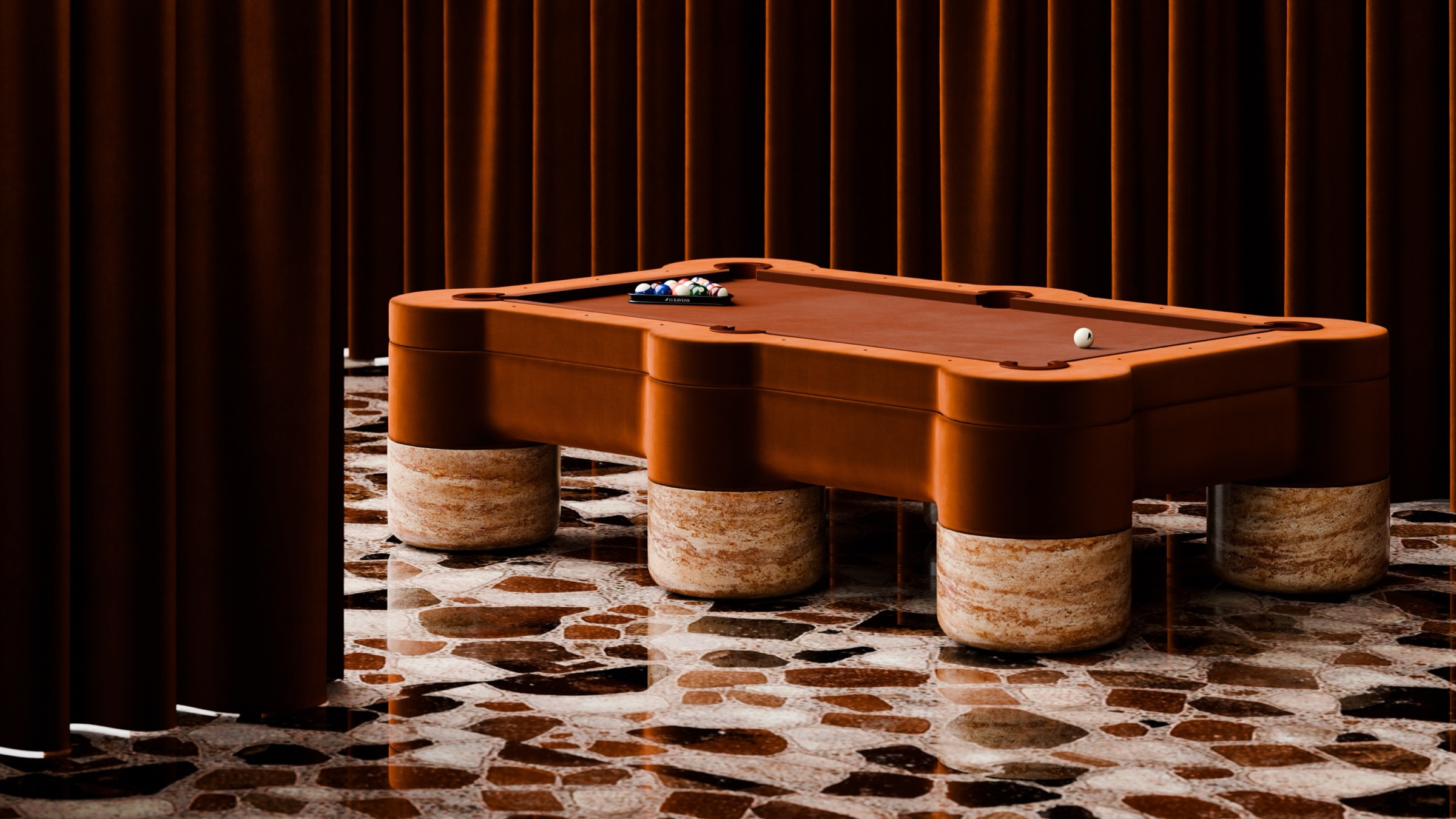 A modern Marc Ange Pool Table with rounded edges and thick legs sits on a patterned stone floor, surrounded by tall brown curtains. A cue ball and racked balls rest on the table.