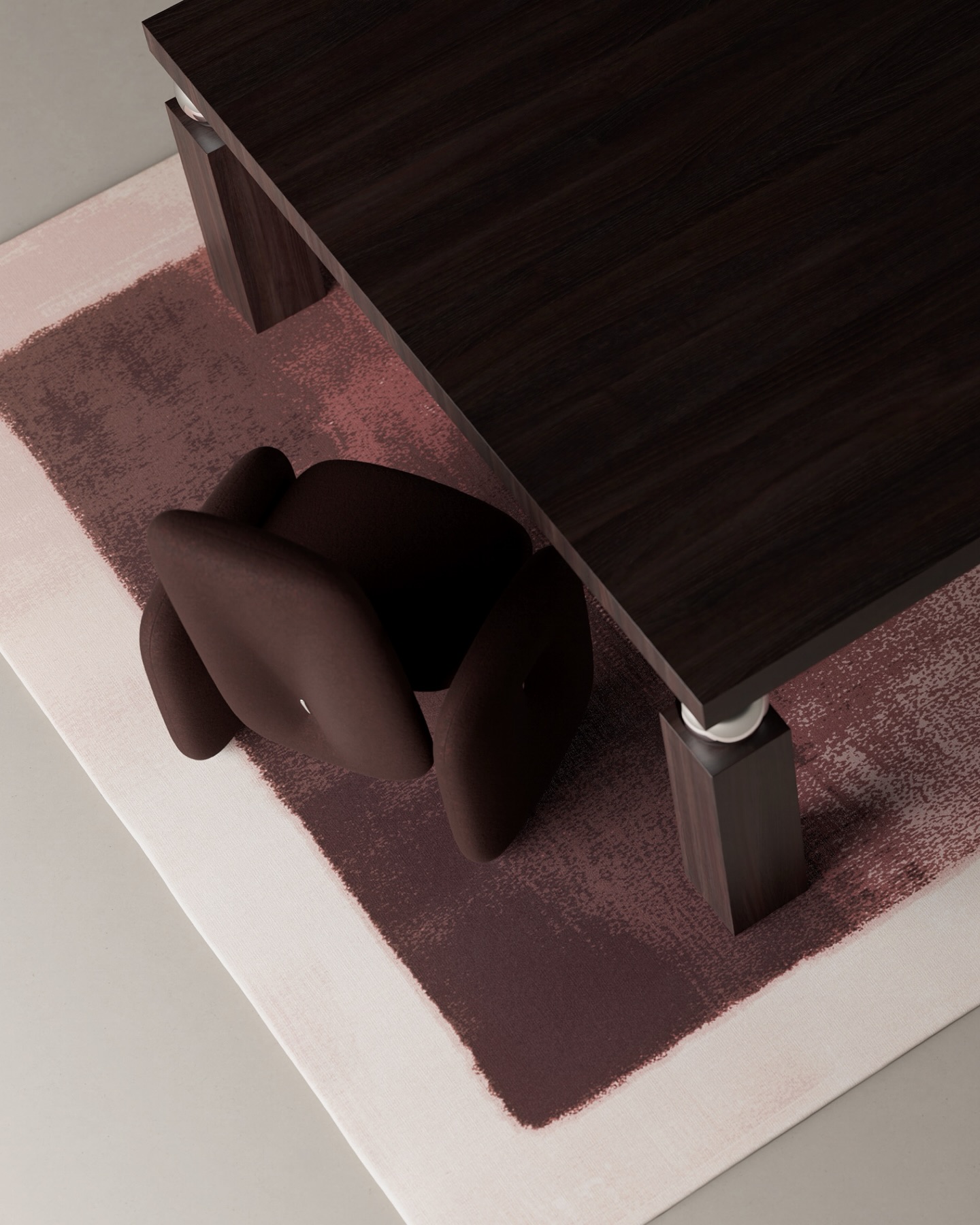 A dark wooden table and a burgundy, modern-shaped chair sit on a rectangular, pink and burgundy area rug in a minimalist setting, viewed from above.