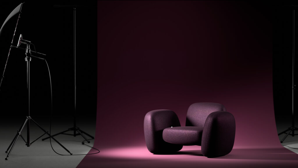 A modern, rounded purple armchair sits on a pink floor in front of a matching pink backdrop, with studio lighting equipment visible on the left side of the image.