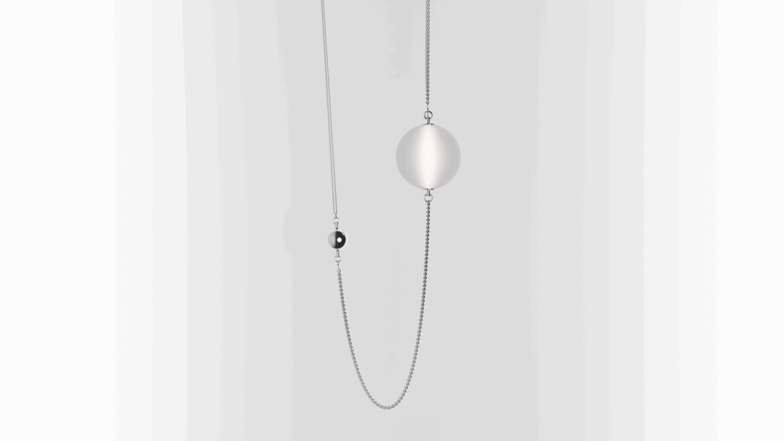 A minimalist necklace with a thin silver chain featuring a small black bead and a larger, flat, circular silver pendant, displayed against a light gradient background.