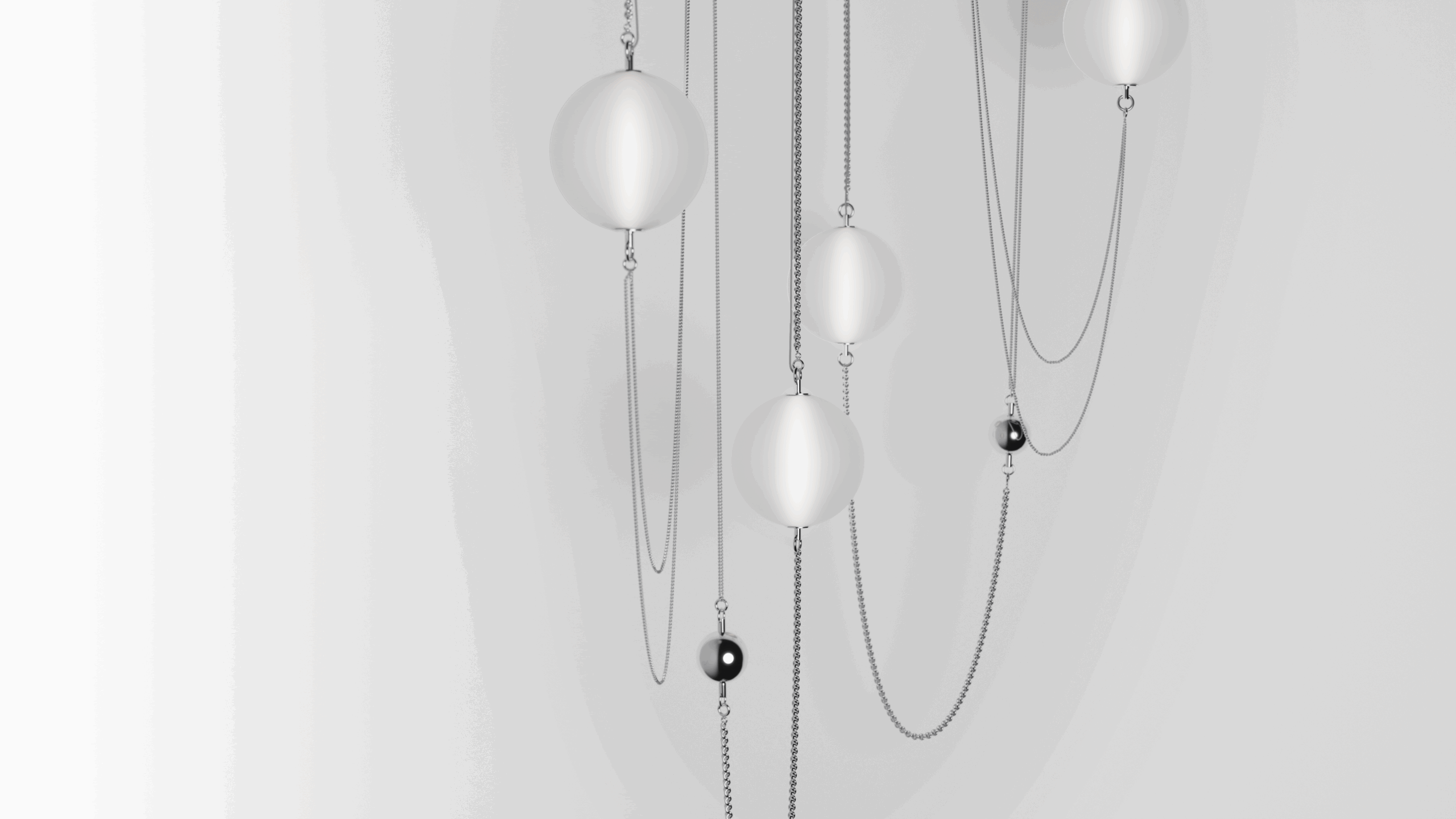 Abstract image featuring silver chains and white and black spherical ornaments hanging against a light gray background, creating a minimalist and modern composition.