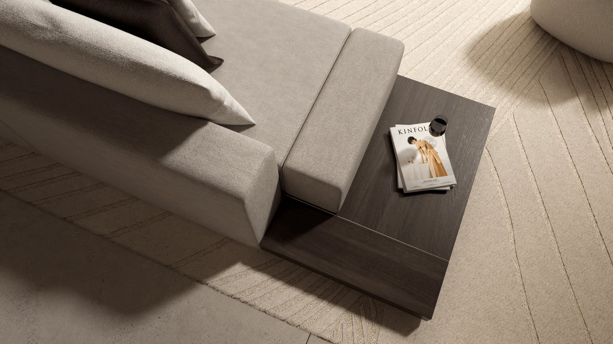A modern beige sofa with a wooden side table attached; on the table are a magazine titled Kinfolk and a black round object, all set on a textured cream and beige rug.