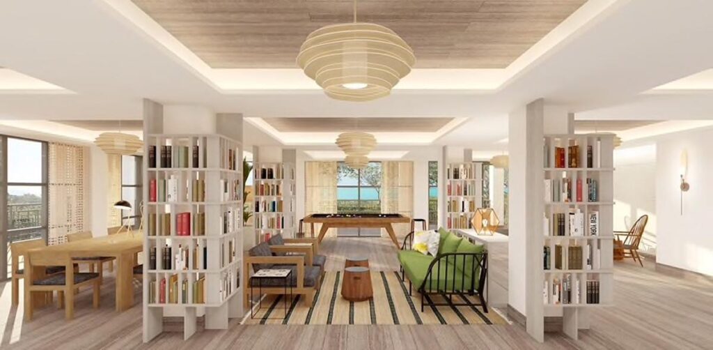 Spacious, modern living area with light wood floors, bookshelves, lounge seating, dining table by 11 Ravens, and large windows revealing a scenic water view. Pendant lights hang from the ceiling. Recent Work &ndash; 11 Ravens.